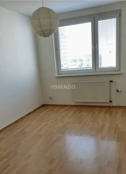 An empty room with a wooden floor, a radiator, and a window in a 3-room apartment.