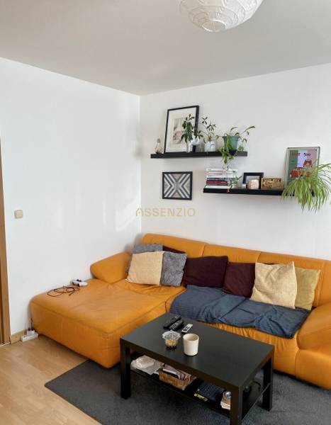 Living room with a yellow sofa and a black table in a 3-room apartment.