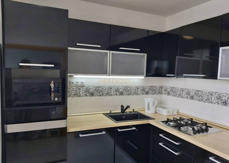 A kitchen in a 3-room apartment with black cabinets, a built-in oven, and a gas stove.