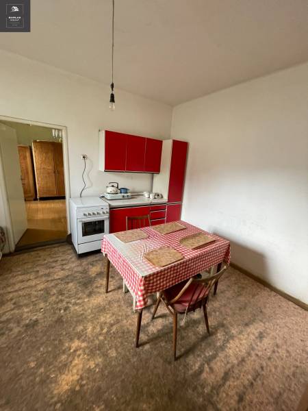 A kitchen in a family house with a dining table and a red kitchen unit.