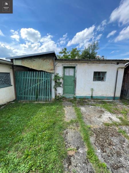 A family house in Trenčianske Stankovce with green doors, a small window, and a lawn.