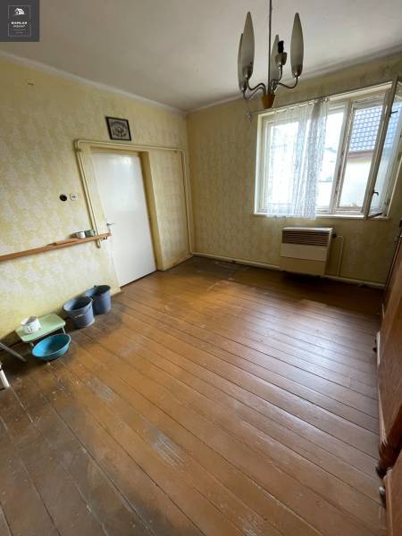 The interior of a family house with wooden flooring, older furniture, and a hanging light fixture.