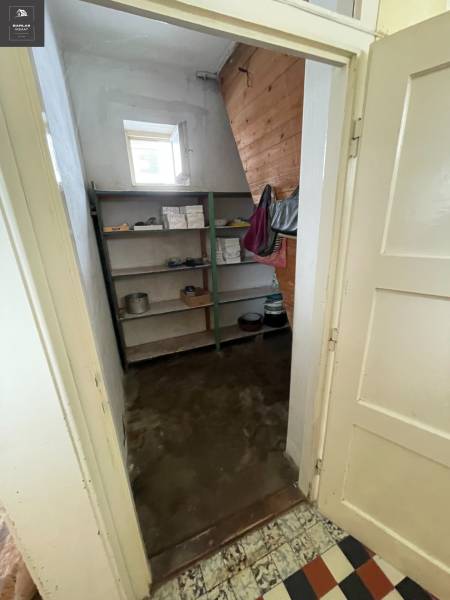 A pantry in a family house with shelves, an open window, and wooden wall paneling.