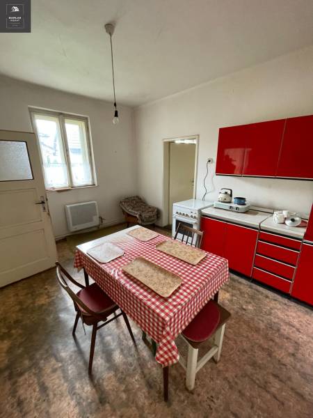 A kitchen in a family house with a red kitchen unit and a dining table.