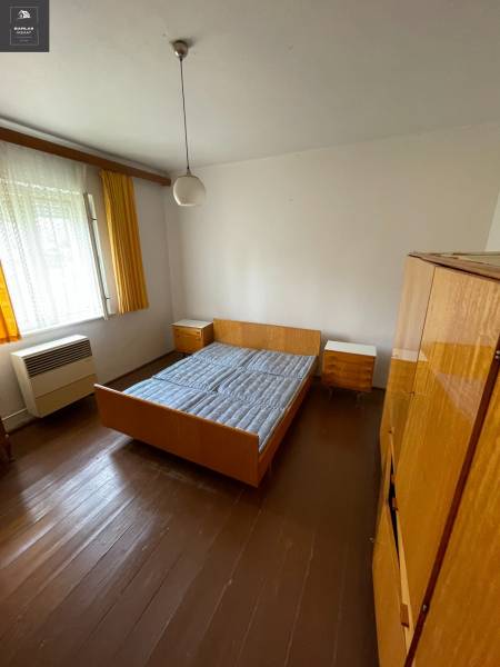Bedroom in a family house with wooden flooring, bed, and cabinets.