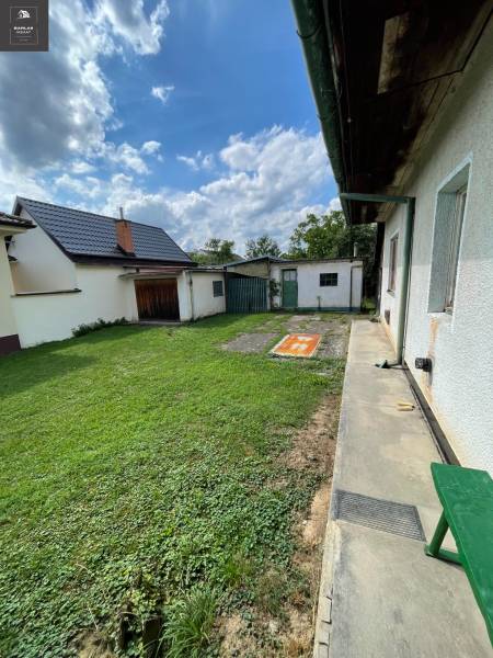The garden of a family house in Trenčianske Stankovce with a green lawn and an extension.