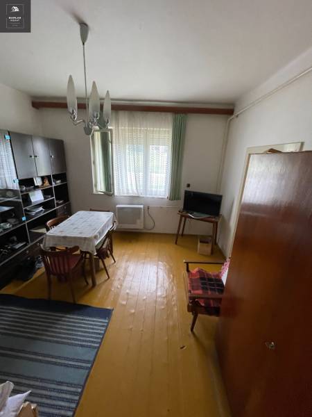 Dining room in a family house with wooden flooring, a simple table, and a cabinet on the wall.