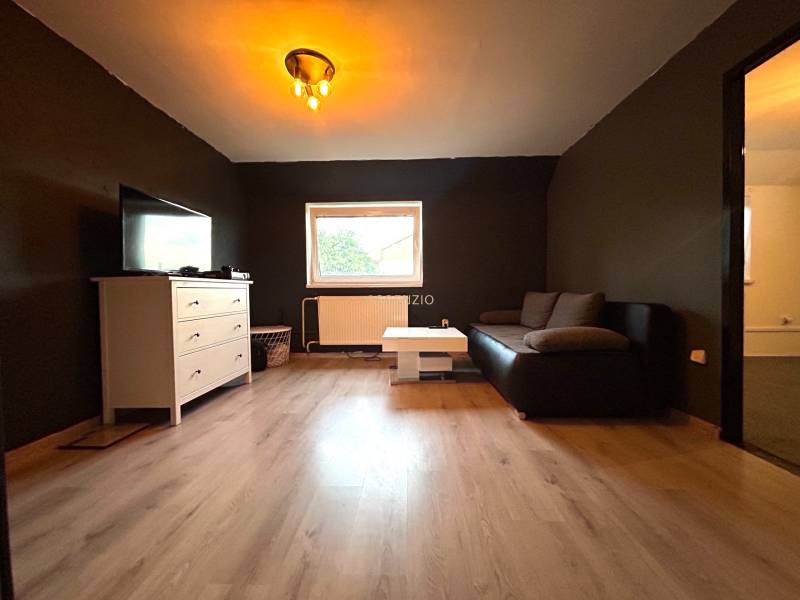 Living room in a 4-room apartment with a black couch and a white sideboard.