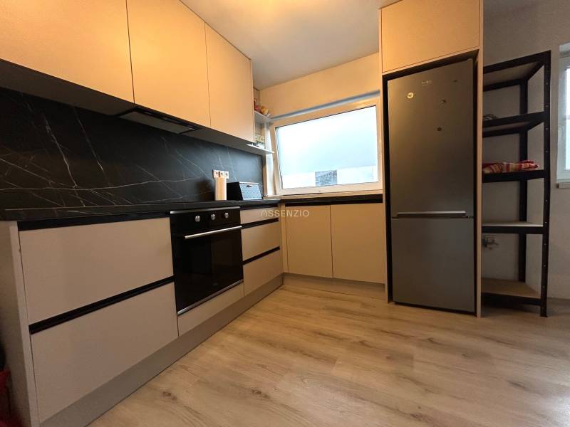 A kitchen in a 4-room apartment with black tiles and built-in appliances.