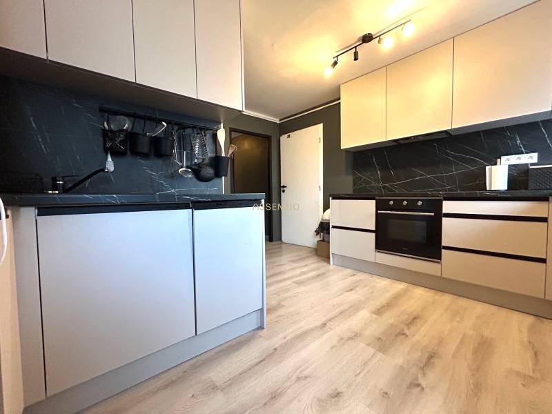 A kitchen with white cabinets in a 4-room apartment, equipped with a dark countertop.