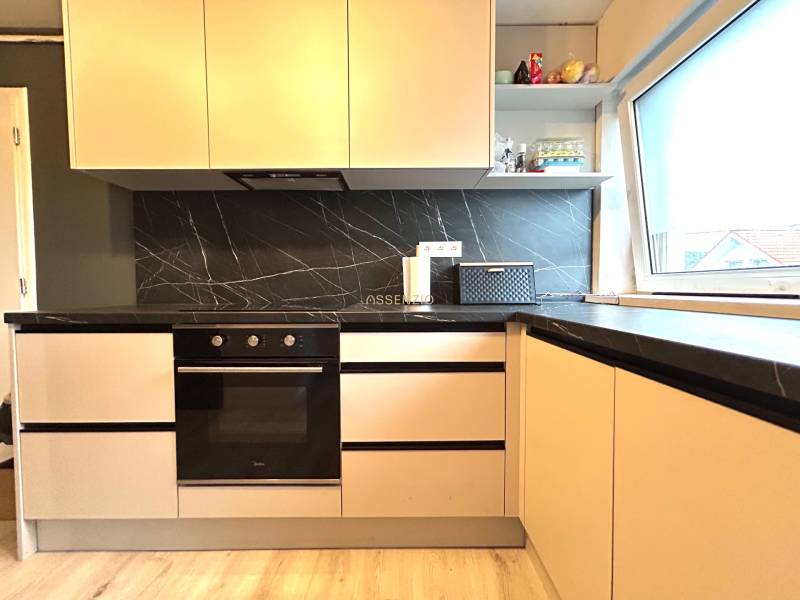 A kitchen in a 4-room apartment with black tiles and light cabinets.