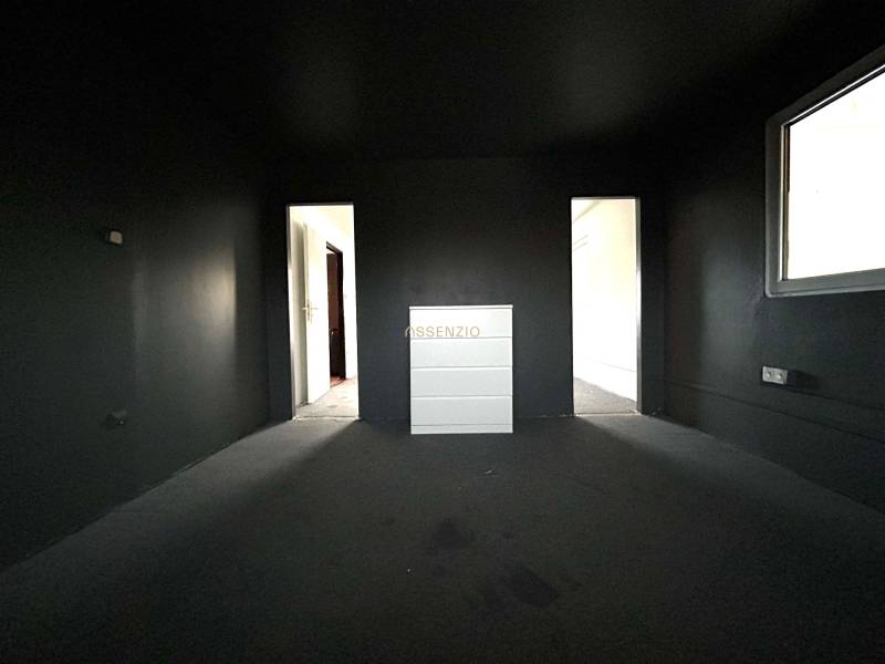 A dark room in a 4-room apartment with a chest of drawers and entrances to other rooms.