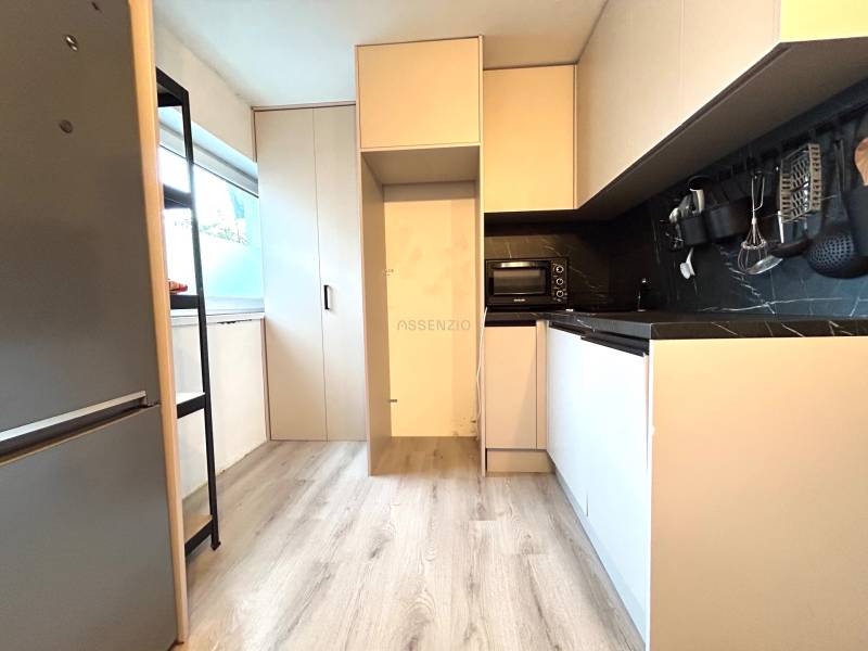 A kitchen in a 4-room apartment with wooden flooring, built-in appliances, and storage space.