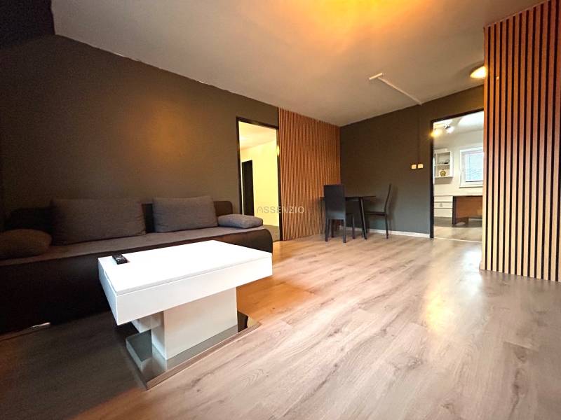 Living room with a gray sofa, white table, and dining area in a 4-room apartment.