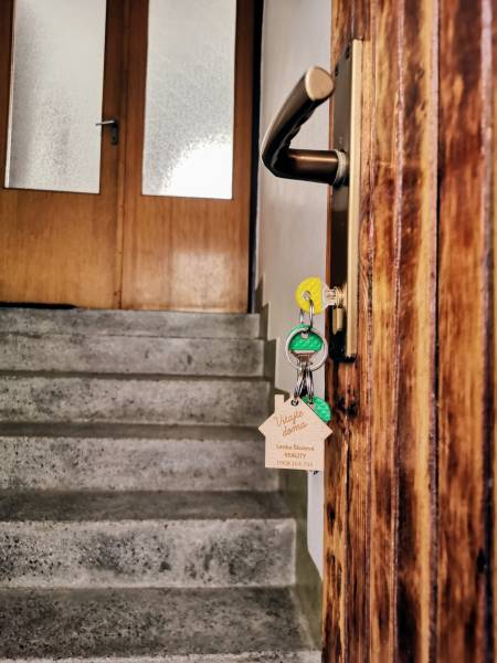 Wooden door with a handle and keys leads to the staircase in a family house.