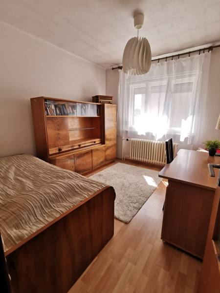 A room in a family house with wooden furniture, a bed, and a rug.