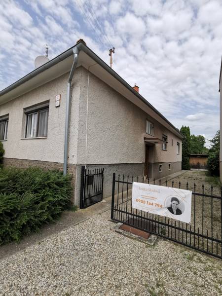 A family house in Topoľčianky with an entrance and gate on a gravel road.