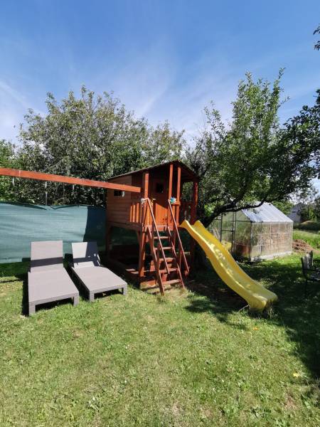 The garden of a family house in Topoľčianky with a children's playhouse, slide, and loungers.