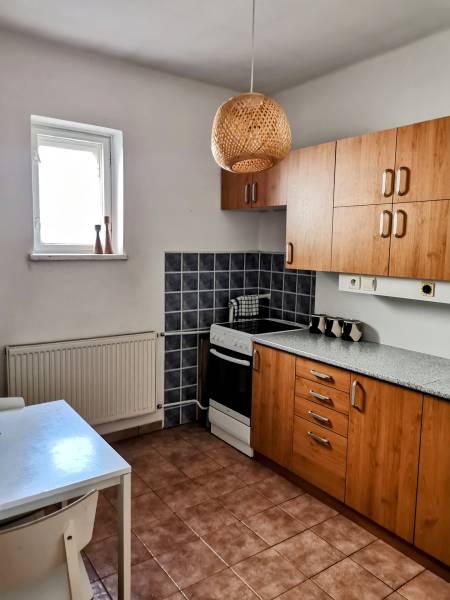 A kitchen in a family house with wooden cabinets, a stove, and a white table.