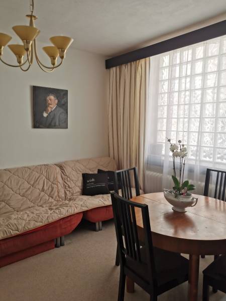 Interior of a family house with a dining table, an armchair, and a painting on the wall.