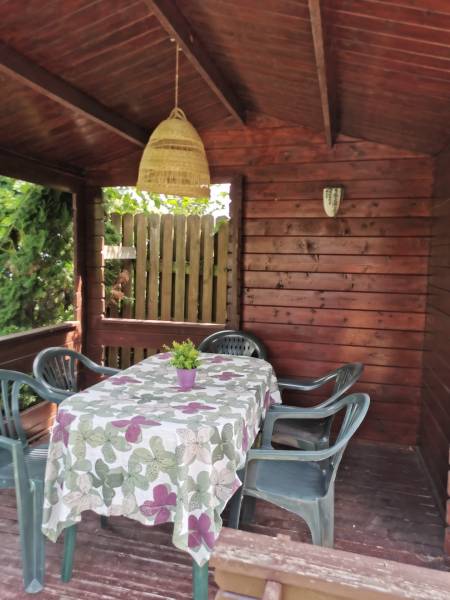 A wooden gazebo in a family house in Topoľčianky, with plastic chairs and a decorated table.