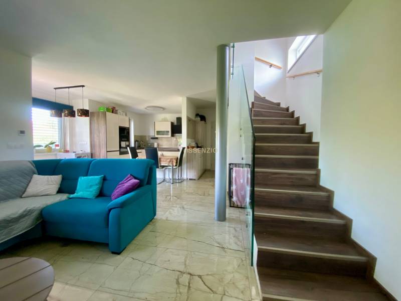 Living room with kitchen in a family house, staircase, comfortable couch, and dining table.