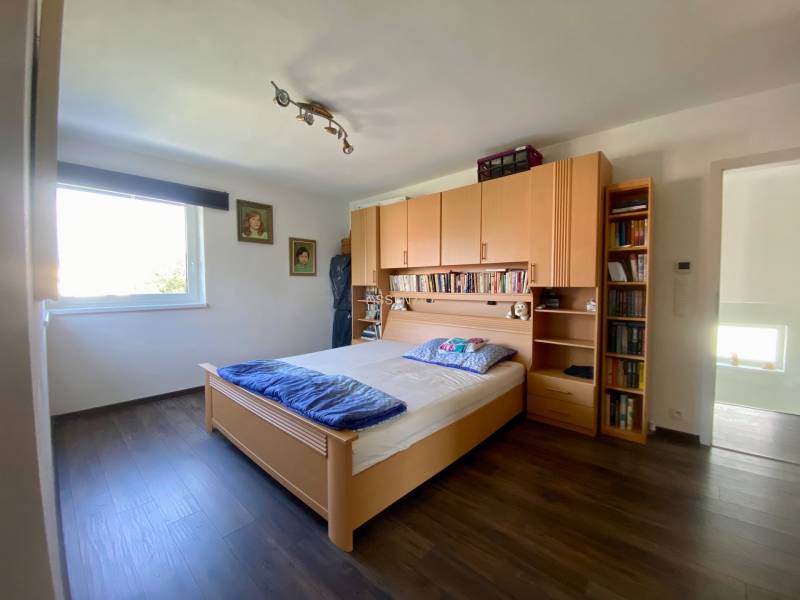 Bedroom with a bed, wooden furniture, and a bookshelf in a family house.