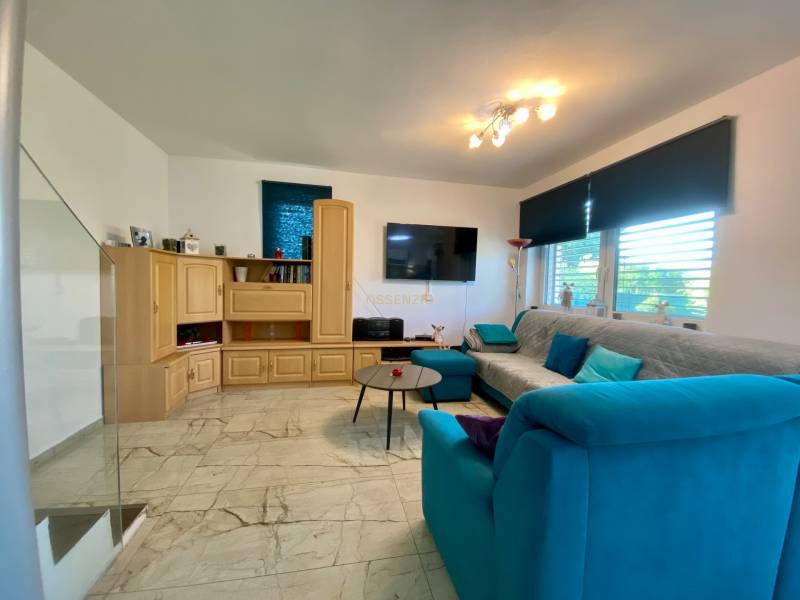 Living room with a light floor, wooden cabinet, and blue sofa in a family house.
