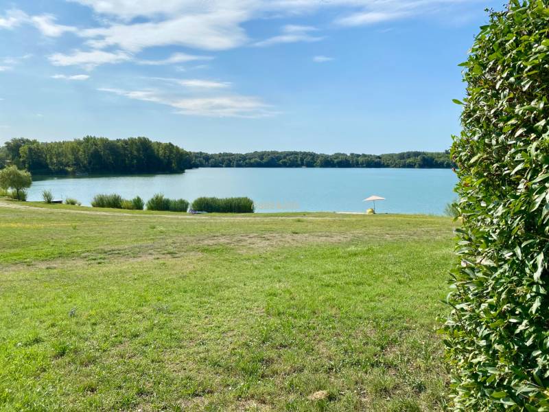 A peaceful body of water by a family house in Vojka nad Dunajom with greenery and an umbrella.
