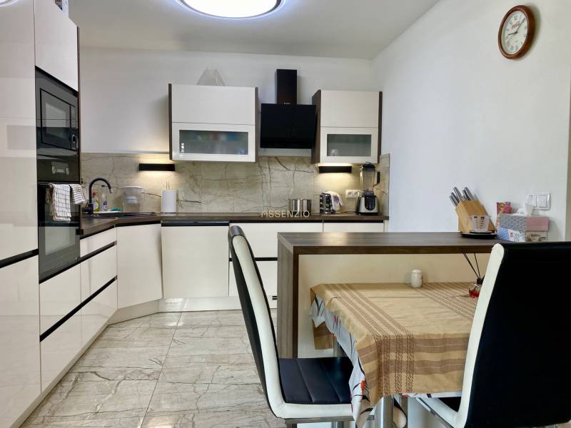 A kitchen in a family house, equipped with appliances, a dining table with chairs.