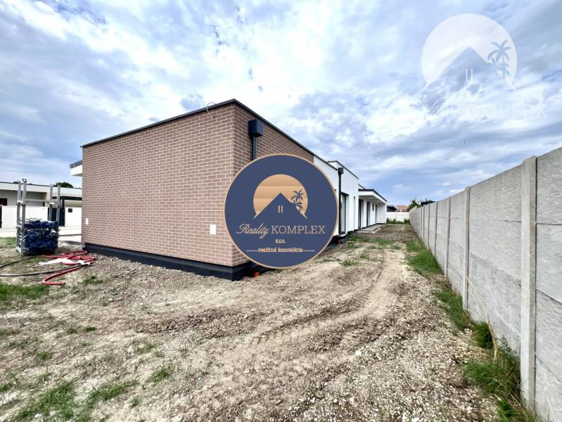 A family house in Miloslavov with a brick facade and a plot next to a concrete fence.