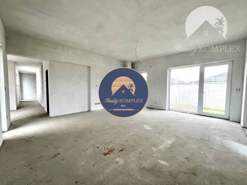 Interior of a family house with large windows and an empty concrete floor.