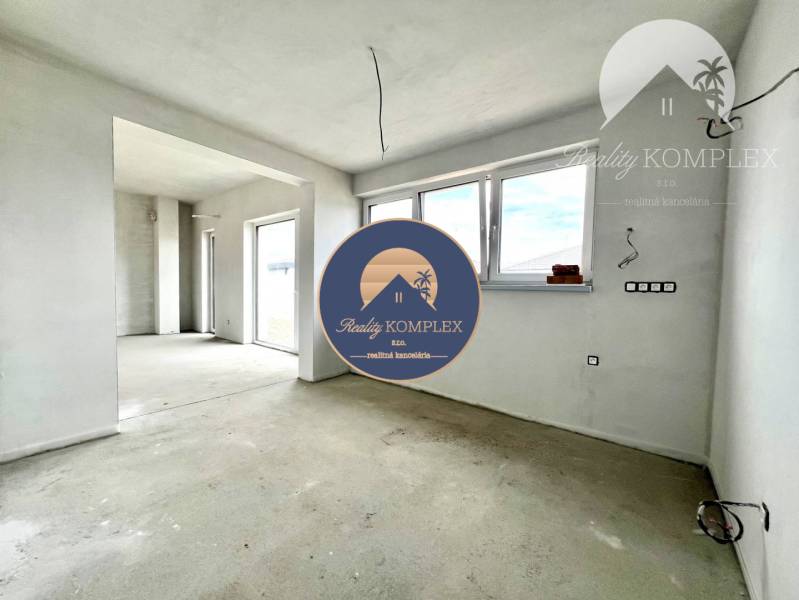 An empty room in a family house with three large windows and a concrete floor.