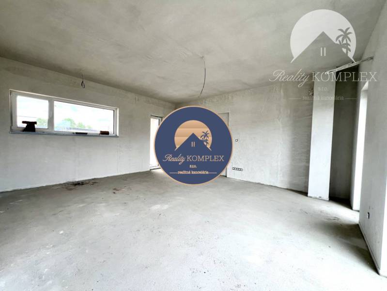 Spacious, unfinished room in a family house with a window and a door.