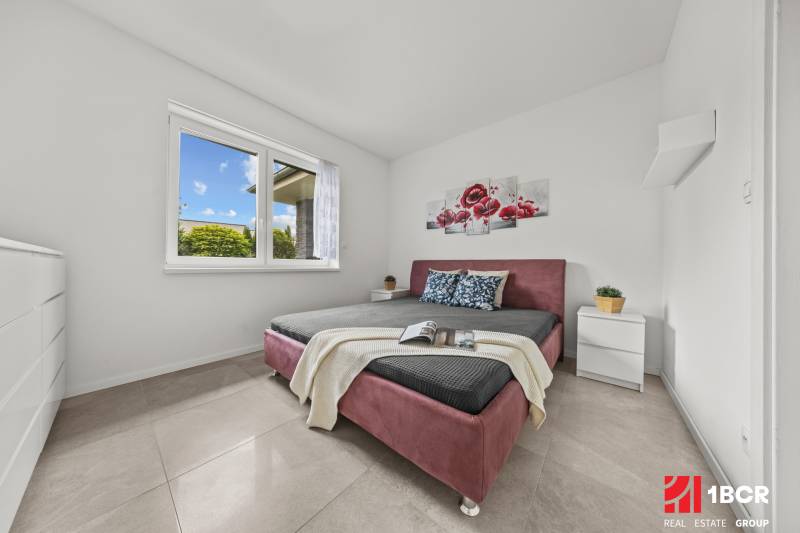 Bedroom in a family house with a double bed, a flower painting, and nightstands.