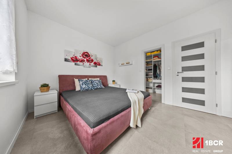 Bedroom with a built-in wardrobe, bed, and decoration with red flowers in a family house.