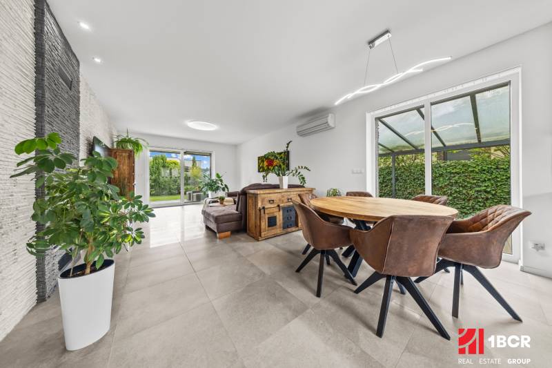 Interior of a family house with a dining area, leather chairs, and a view of the garden.