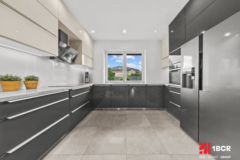 A spacious kitchen in a family house with modern appliances and a view from the window.