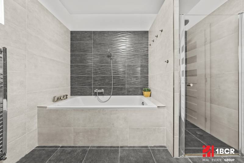 Gray bathroom with a bathtub and a shower in a family house.