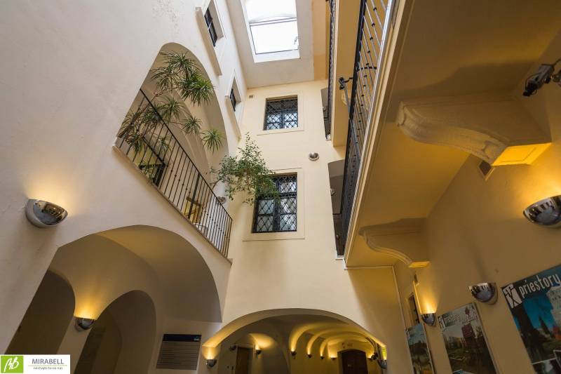 The interior of an office with a glass ceiling, balconies, and plants.