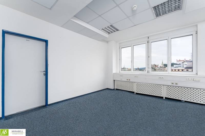 View from an office with light-colored walls and blue carpet, overlooking Bratislava Castle.