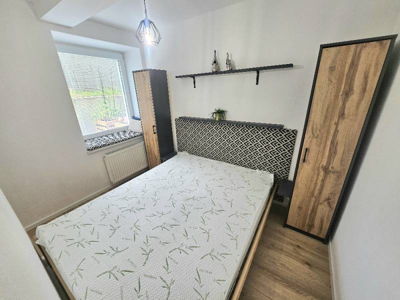 Bedroom in a studio apartment with a bed, cabinet, and decorations on the shelf.