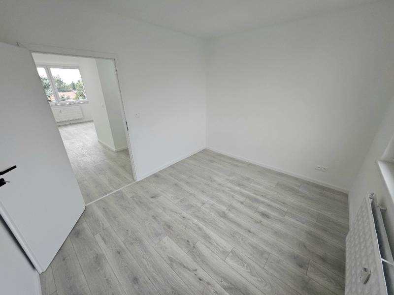 A bright room in a 3-room apartment with laminate flooring and open doors.