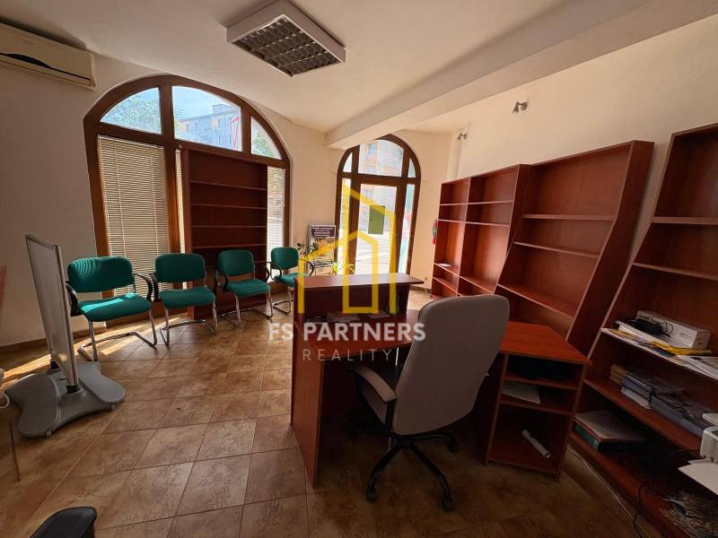 Commercial premises with an office chair, green armchairs, and wooden shelves.