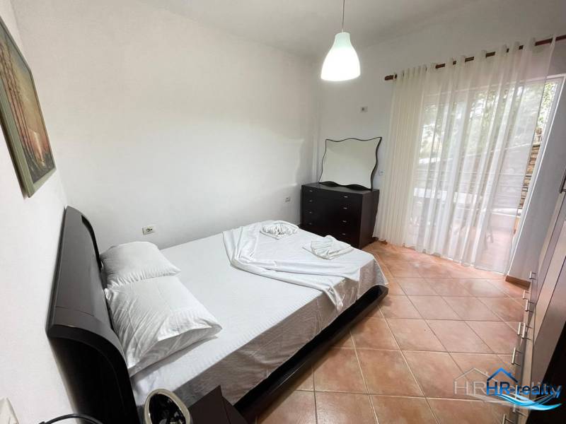 Bedroom in a holiday apartment with a double bed, dresser, and balcony.