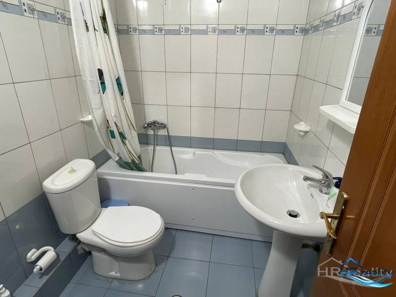 Bathroom in a holiday apartment, with a bathtub, sink, and toilet.