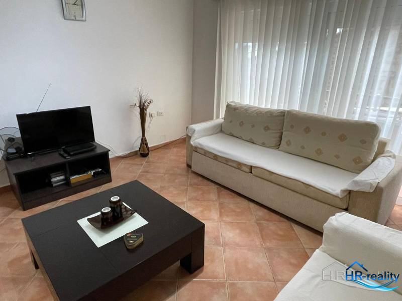 Living room in a holiday apartment with sofas, a table, and a television.