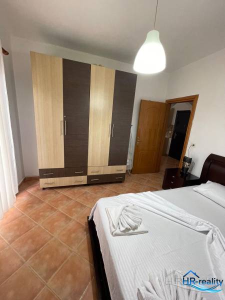 Bright bedroom in a holiday apartment with a bed, wardrobe, and tiled floor.