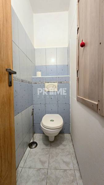 A bathroom with light blue tiles in a three-room apartment.
