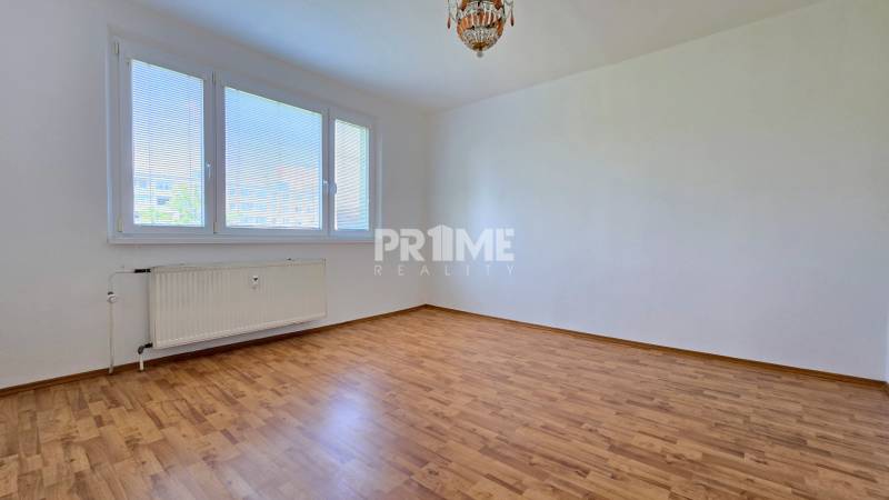 A bright room with a large window, wooden floor, and radiator in a 3-room apartment.